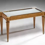 Table basse rectangulaire du salon de musique de première classe du paquebot Liberté, réalisée vers 1950, en bouleau de Norvège avec plateau miroir, piètement fuselé et détails en métal doré.