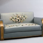 Canapé deux places du salon de musique de première classe du paquebot Liberté, réalisé vers 1950, avec revêtement bleu-gris orné d’une tapisserie florale d’Aubusson et accotoirs en bouleau de Norvège.
