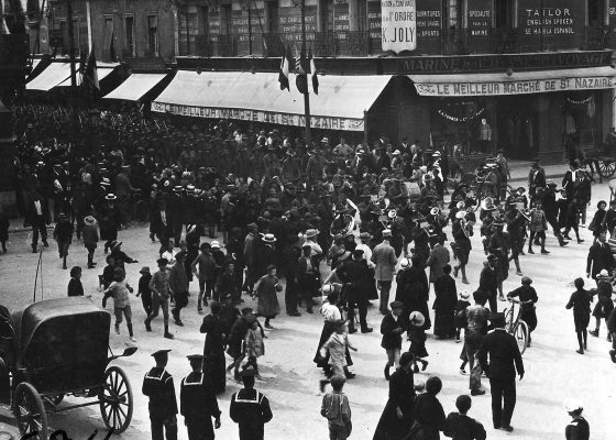 Foule composée de Nazairiens de tous âges assistant à une parade américaine au moment du débarquement à Saint-Nazaire pendant la Première Guerre mondiale.