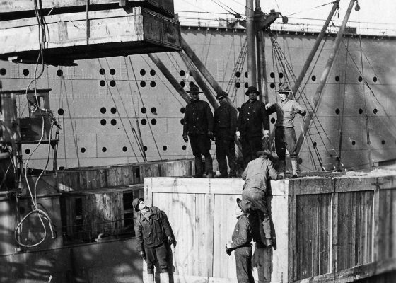 Soldats américains déchargeant d'énormes caisses en bois d'un navire avec une grue sur un quai à Saint-Nazaire pendant la Première Guerre mondiale.