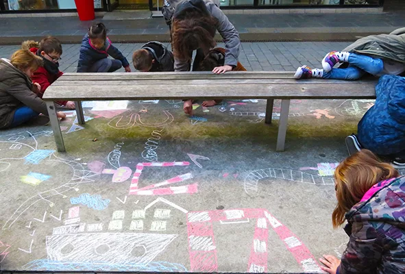 Photographe : École élémentaire publique Paul Bert Jeunes élèves de primaire dessinant à la craie sur le sol dans la ville près du centre commercial le Paquebot.