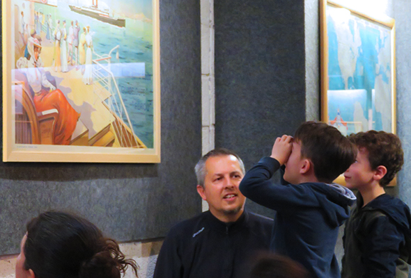 Jeune élève de primaire regardant une affiche en mimant des jumelles avec ses mains devant ses yeux lors d'une visite scolaire à l'Écomusée, musée d'histoire de Saint-Nazaire.