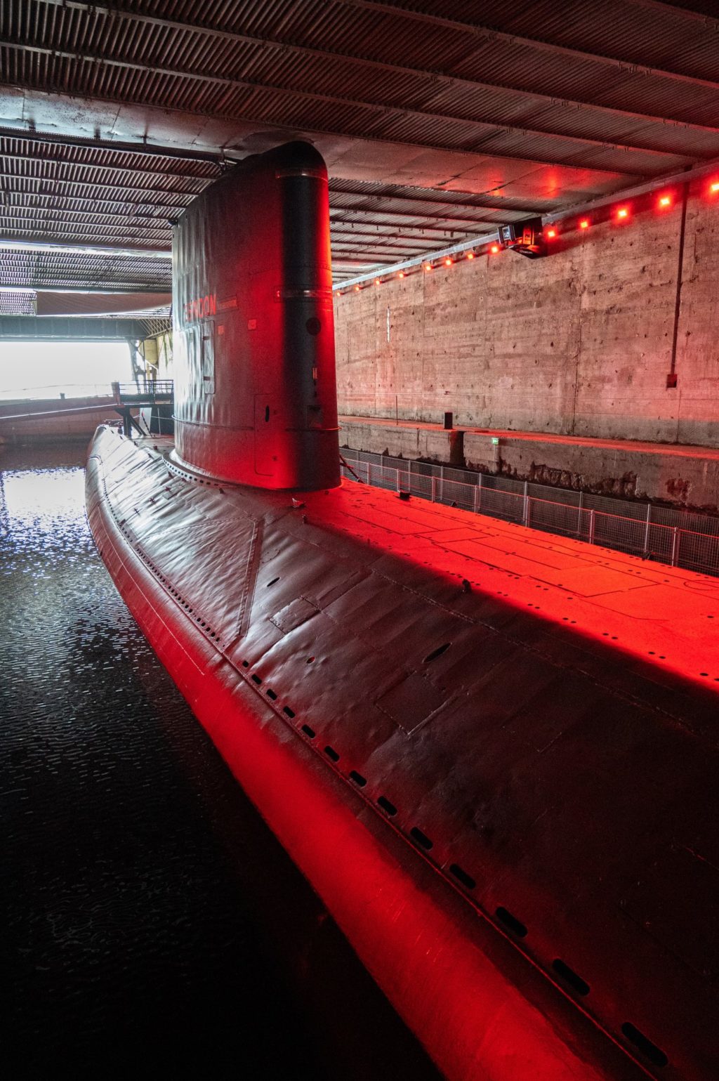 Sous-marin Espadon éclairé en rouge dans l'écluse fortifiée.