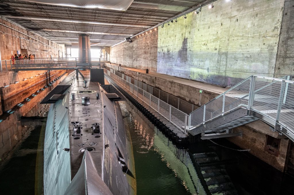 Vue sur la proue du sous-marin Espadon, au fond quelques visiteurs marchent sur la passerelle de sortie.