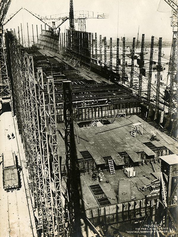 Vue aérienne d'ouvriers procédant au montage des barreaux et membrures ainsi qu'à l'assemblage des ponts du paquebot Ile-de-France.