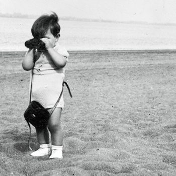 Petit garçon regardant à travers des jumelles sur une plage.