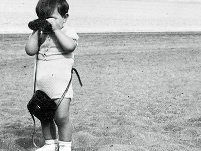 Petit garçon regardant à travers des jumelles sur une plage.