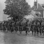 Colonne de soldats américains longeant une maison dans la campagne nazairienne.