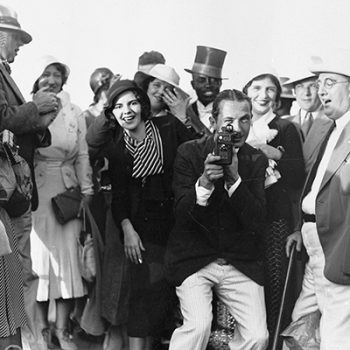 Groupe de personnages posant autour d'un photographe qui fait face à l'objectif.