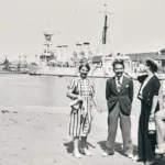Quatre femmes et un homme posant devant le bassin du port de Saint-Nazaire et un navire militaire.
