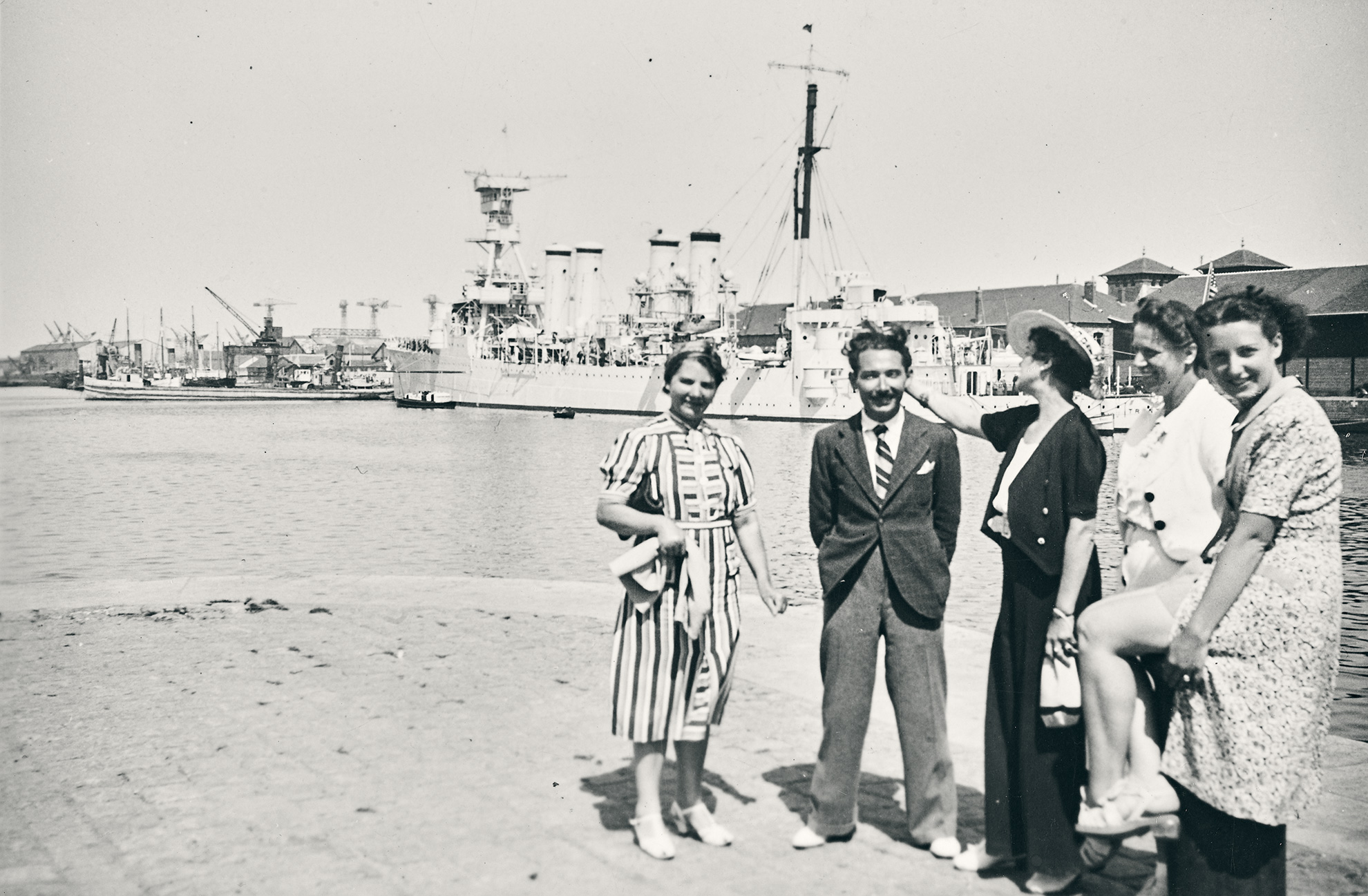 Quatre femmes et un homme posant devant le bassin du port de Saint-Nazaire et un navire militaire.