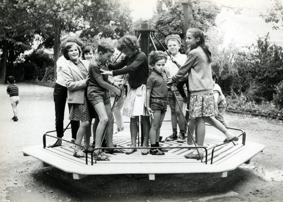 Des enfants jouent sur un tourniquet dans un parc en juillet 1963.