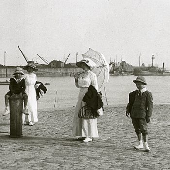 Deux femmes en robes blanches du début du siècle posent avec deux enfants au niveau de l'avant-port de Saint-Nazaire.