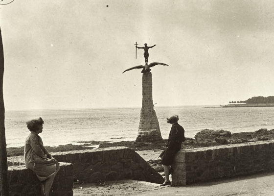 Deux femmes assises sur un muret sur le front de mer regarde le monument américain dressé à la suite de la Première Guerre mondiale dans les années 1930.