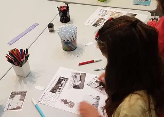 Photographie prise au-dessus de l'épaule d'une jeune fille sur le roman-photo qu'elle est en train de réaliser à l'aide de photographies et de crayons.