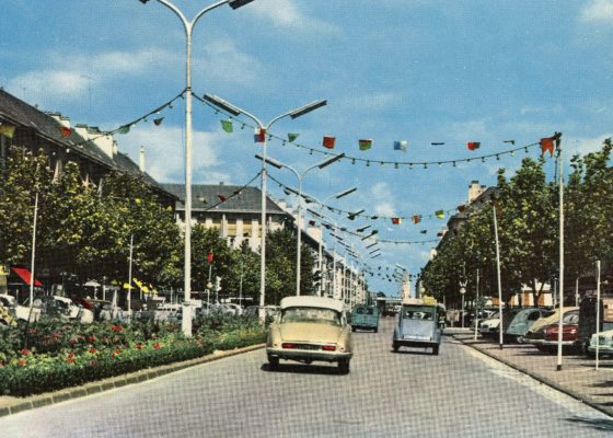 Voitures des années 1950 roulant sur l’avenue de la République pavoisée à Saint-Nazaire.