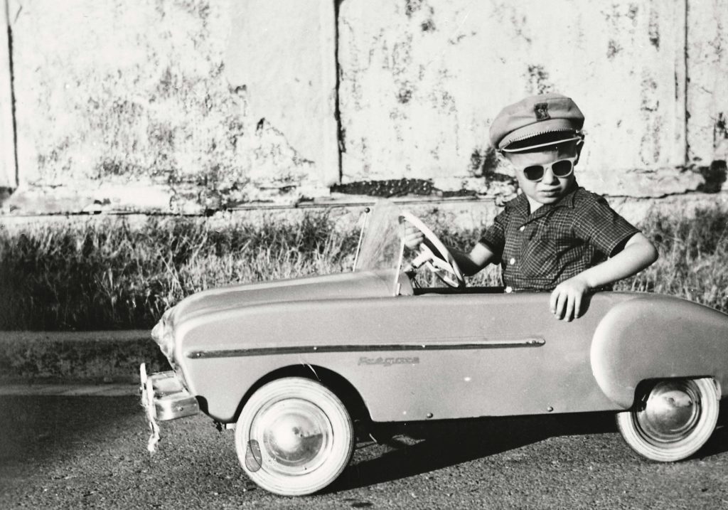 Enfant au volant d’une voiture-jouet Renault Frégate.
