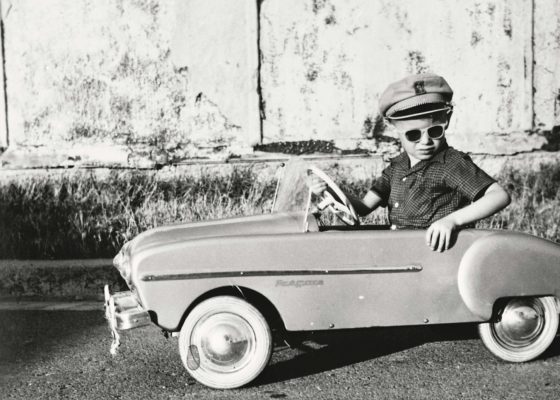 Enfant au volant d’une voiture-jouet Renault Frégate.