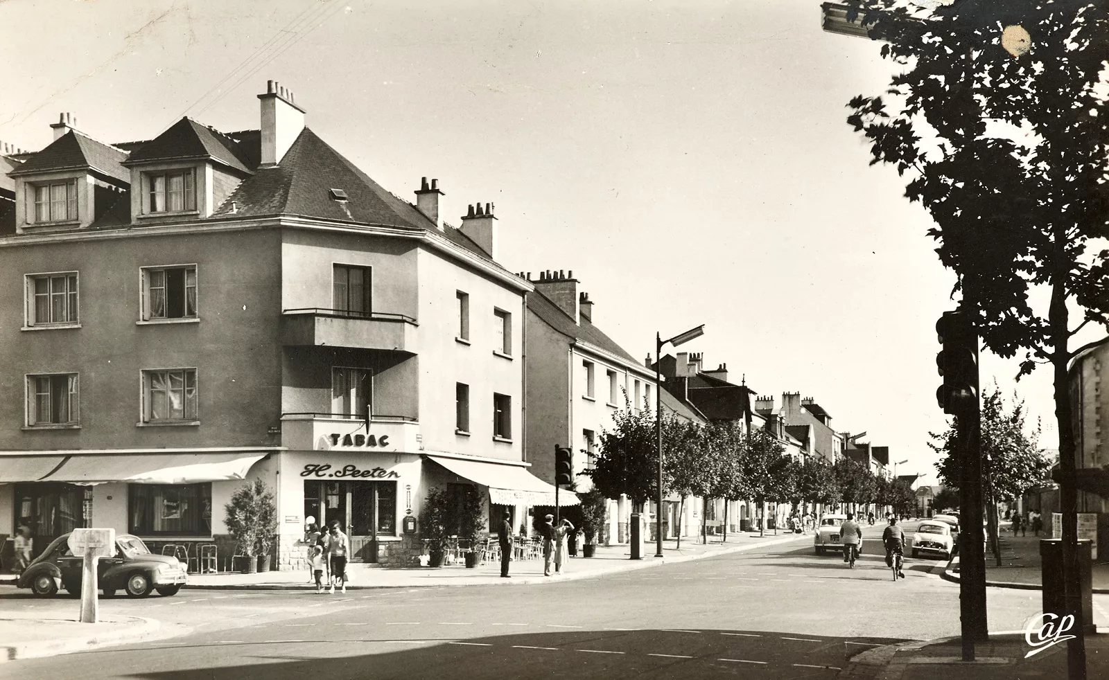 Photographe et éditeur : CAP. Collection Saint-Nazaire Agglomération Tourisme-Écomusée Photographie noir et blanc d'un carrefour dans le centre-ville de Saint-Nazaire avec un bar.