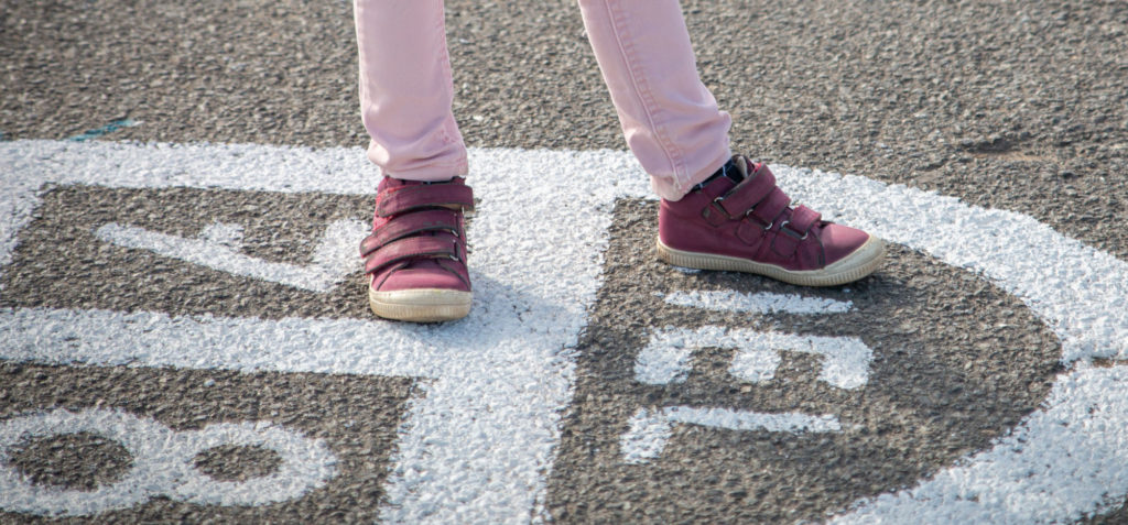 Gros plan sur les jambes d'une enfant qui joue à la marelle.