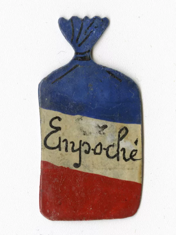 Créatrice : Gilberte Queruau Lamerie. Collection Saint-Nazaire Agglomération Tourisme – Écomusée. Don Gilberte Queruau Lamerie. Insigne en forme de petit sac arborant les couleurs du drapeau français, au centre le mot "empoché" en référence à la Poche de Saint-Nazaire.