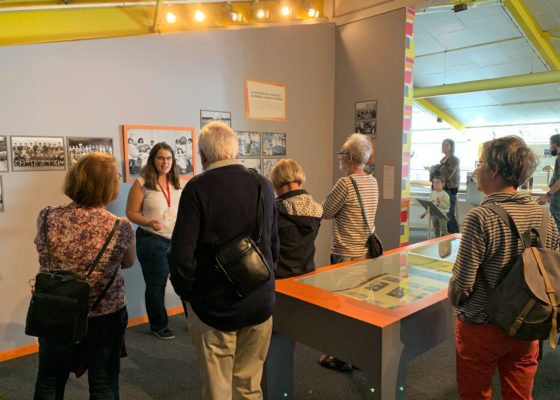 Photographe : Jérôme Bosger Groupe de visiteurs devant une médiatrice dans la salle d'exposition de l'Écomusée