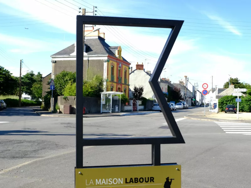 Photographe : Pierre Laisne Vue de la façade colorée d'une maison à travers un mobilier urbain du parcours "Méan-Penhoët, récits de quartier".