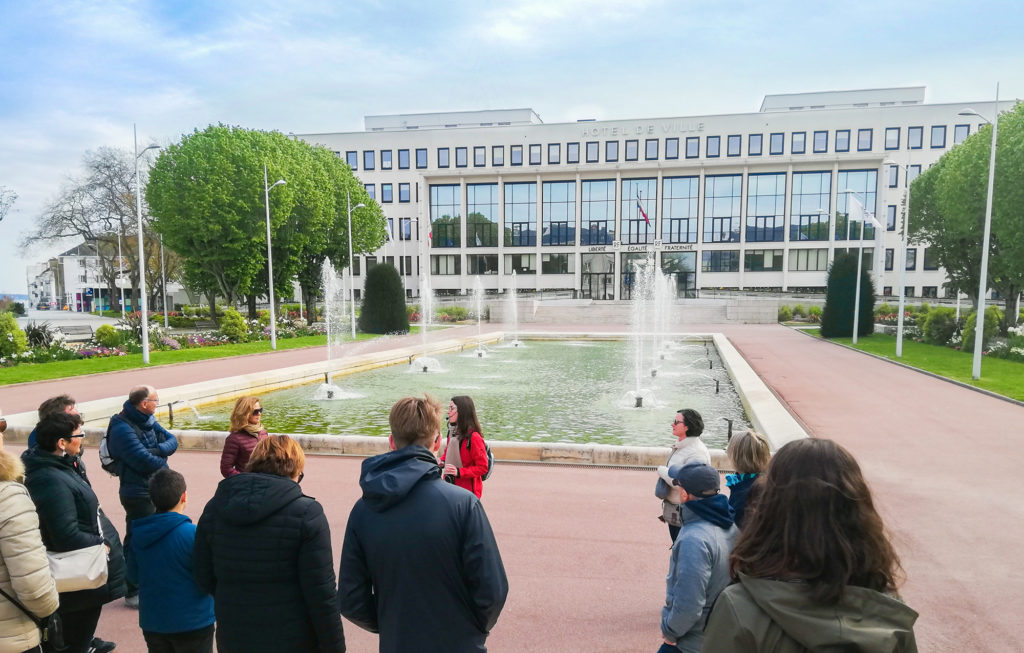 Groupe de personnes suivant une visite face au bassin de l'hôtel de ville à Saint-Nazaire.