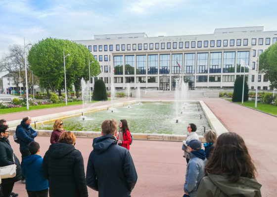 Groupe de personnes suivant une visite face au bassin de l'hôtel de ville à Saint-Nazaire.