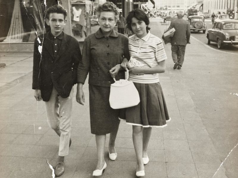 Photographie en noir et blanc d'une femme entourée de deux adolescents marchant dans l'avenue de la République à Saint-Nazaire dans les années 1960.