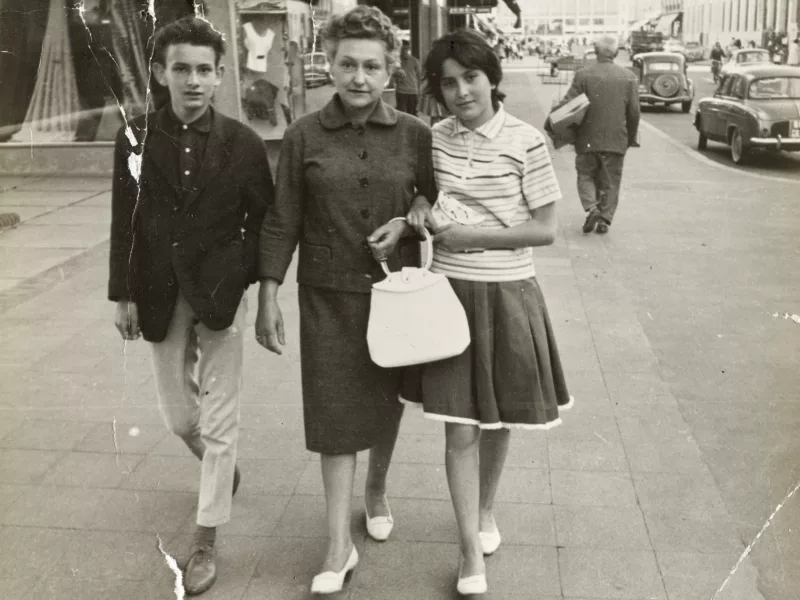 Photographe inconnu. Collection Anne Beaugé. Cliché Saint-Nazaire Agglomération Tourisme-Écomusée Photographie en noir et blanc d'une femme entourée de deux adolescents marchant dans l'avenue de la République à Saint-Nazaire dans les années 1960.