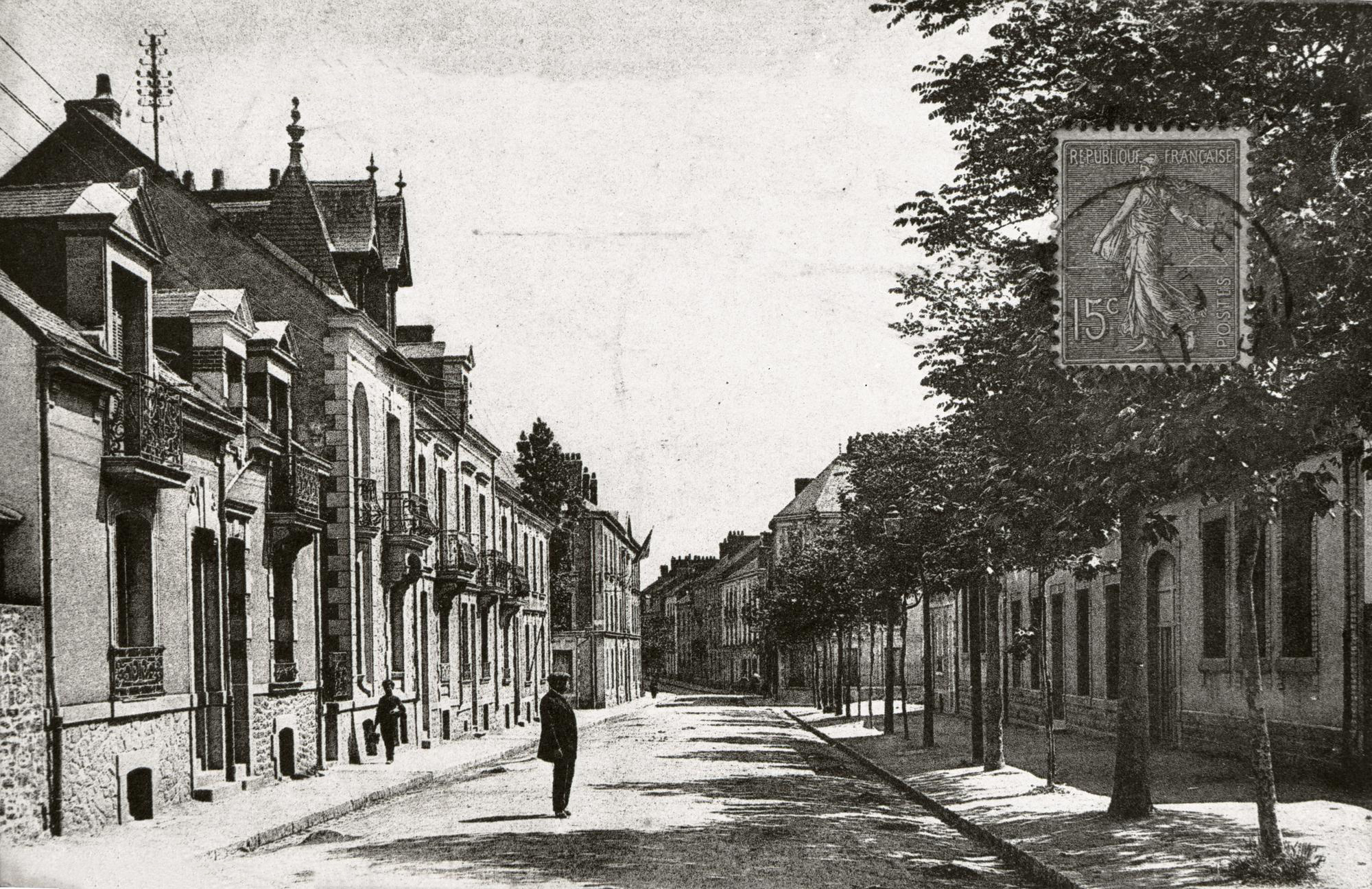 Carte postale en noir et blanc timbrée représentant un homme au milieu d'une rue de Saint-Nazaire vers 1900.