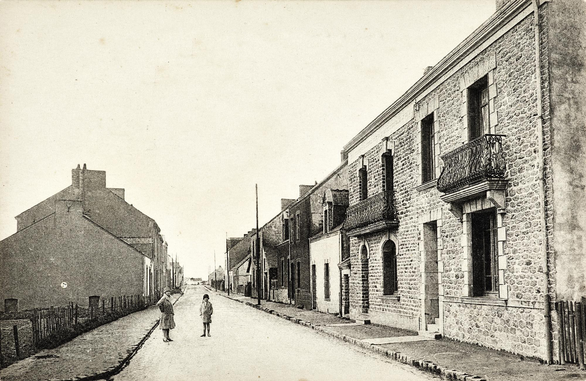 Carte postale noir et blanc représentant une femme et un enfant dans une rue de Saint-Nazaire avant-guerre.
