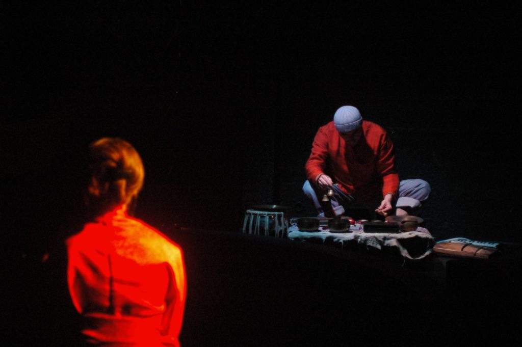 Vue du spectacle Mon navire sur la mer avec une femme en kimono rouge de dos et un joueur de xylophone dans une atmosphère sombre.