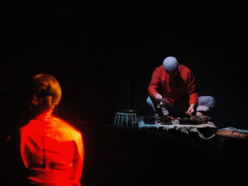 Vue du spectacle Mon navire sur la mer avec une femme en kimono rouge de dos et un joueur de xylophone dans une atmosphère sombre.