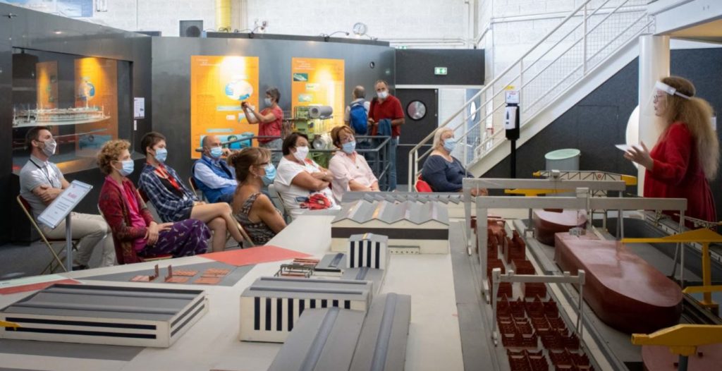 Au premier plan, maquette des chantiers navals, derrière, une dizaine de personnes sont assises et écoute une médiatrice pendant "Ma solidarité" aux Journées du patrimoine.