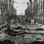 Photographie noir et blanc d'ouvriers travaillant au rivetage de la coque du paquebot Normandie en 1931.
