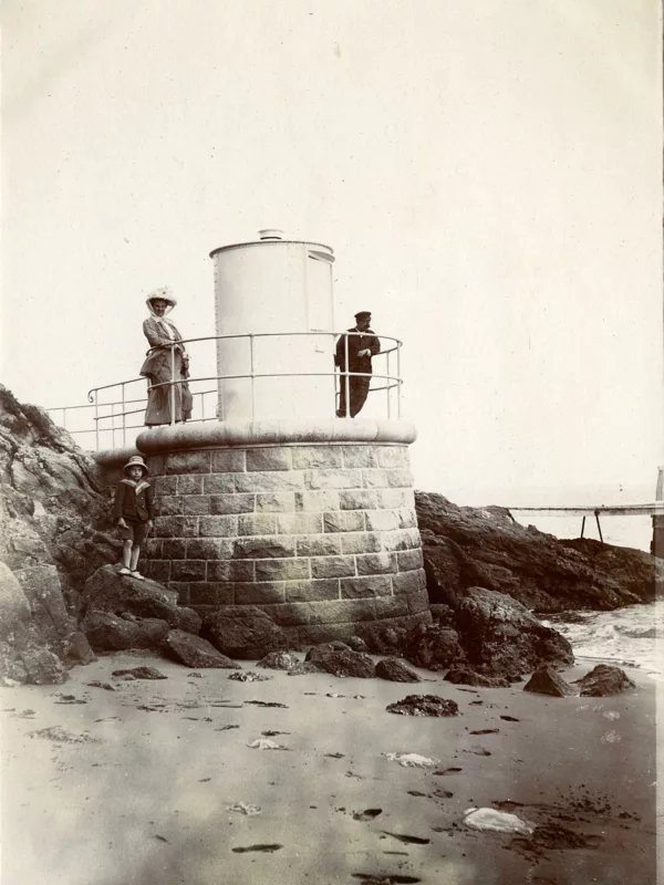 Photographe : inconnu. Collection Saint-Nazaire Agglomération Tourisme – Écomusée. Photographie représentant un homme, une femme et un enfant qui posent devant l'ancien feu antérieur de Porcé, anse de la Belle-Fontaine.