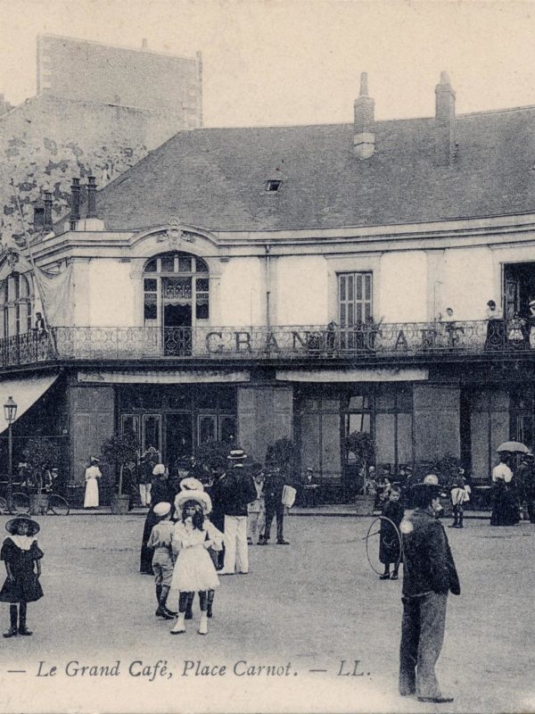 Carte postale avec une photo en noir et blanc représentant une foule devant le Grand Café, place Carnot à Saint-Nazaire.