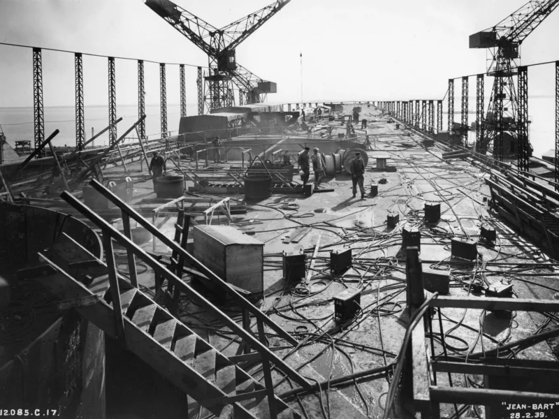 Photographe : Inconnu. Collection Saint-Nazaire Agglomération Tourisme – Écomusée. Fonds Chantiers de l’Atlantique. Montage des superstructures du cuirassé Jean Bart le 28 février 1939.