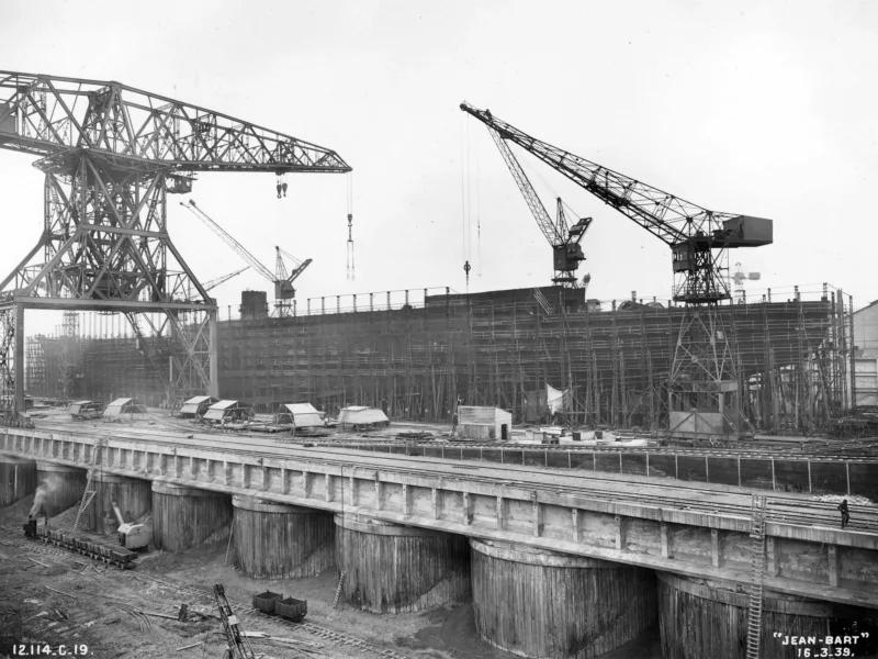 Photographe : Inconnu. Collection Saint-Nazaire Agglomération Tourisme – Écomusée. Fonds Chantiers de l’Atlantique. Montage des bordes du cuirassé Jean Bart le 6 avril 1938.
