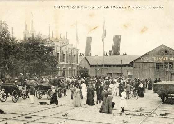 Photographe inconnu. Éditeur : Dugas et Cie. Collection Saint-Nazaire Agglomération Tourisme-Écomusée Foule devant les grilles de l'agence de la Compagnie Générale Transatlantique à Saint-Nazaire vers 1900.