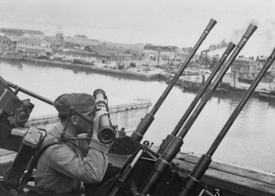 Photographie en noir et blanc illustrant un soldat allemand qui surveille le port depuis le toit du terminal frigorifique.