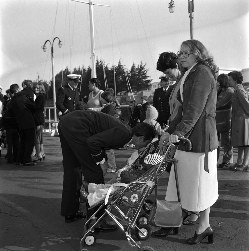 Photographie en noir et blanc d'un soldat embrassant sa famille de retour de mission du sous-marin Espadon