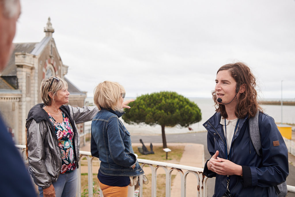 Guide et visiteurs devant l'entrée du port de Saint-Nazaire lors de la visite "La porte du large".