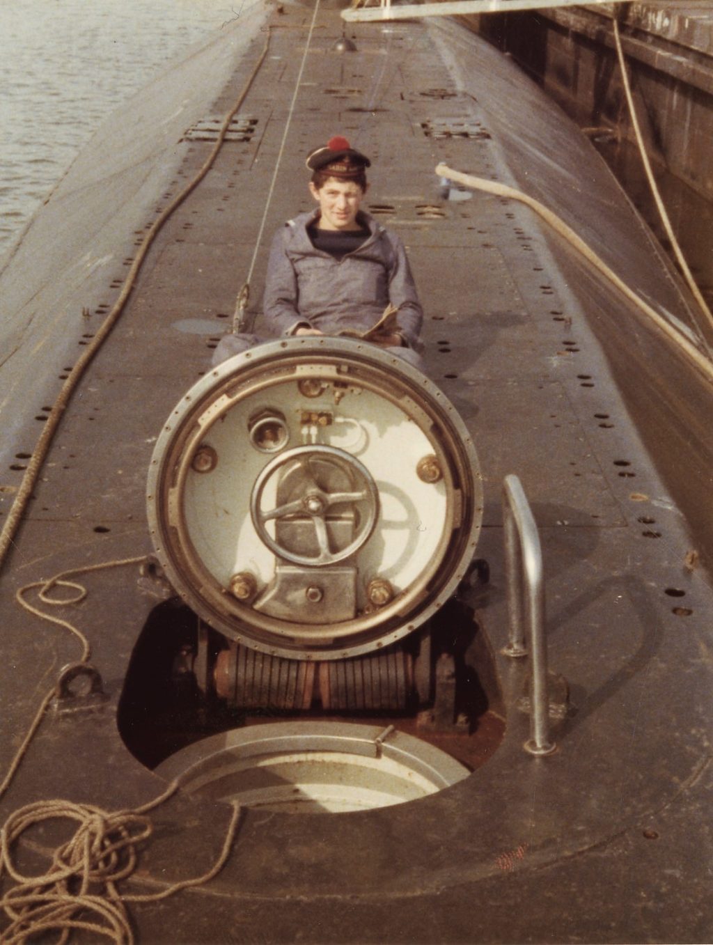 Sous-marinier en uniforme posant devant l'écoutille du sous-marin Espadon. 