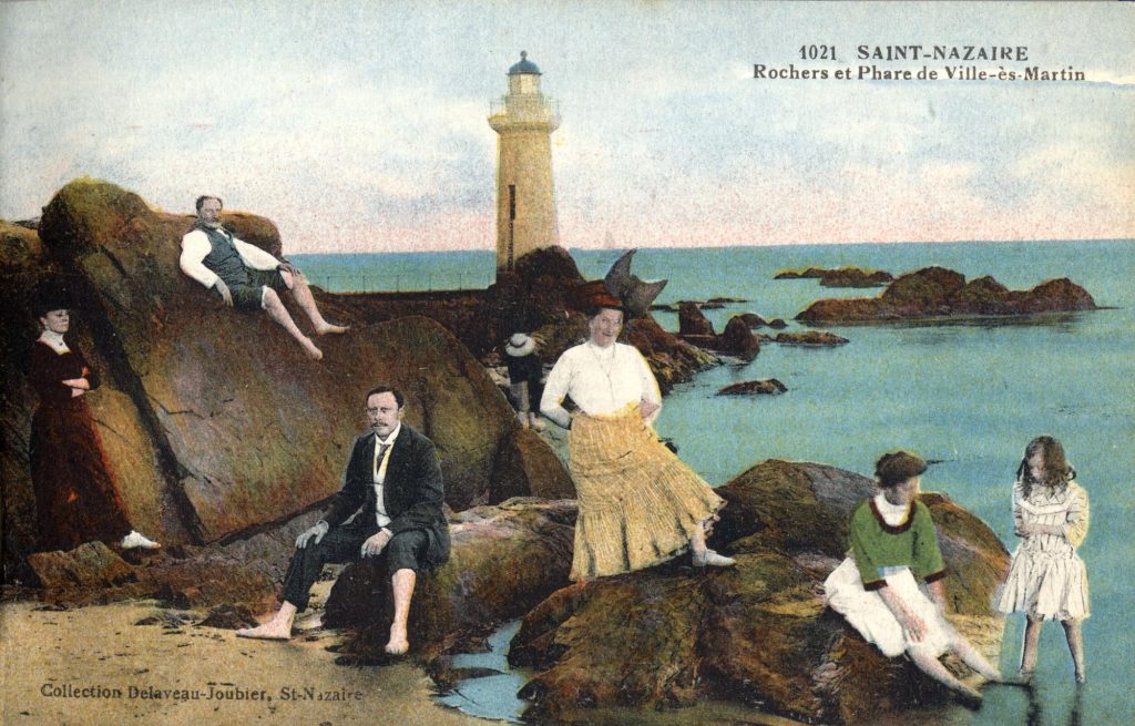 Carte postale représentant une famille posant de façon humoristique sur les rochers de la plage Villès-Martin vers 1910.