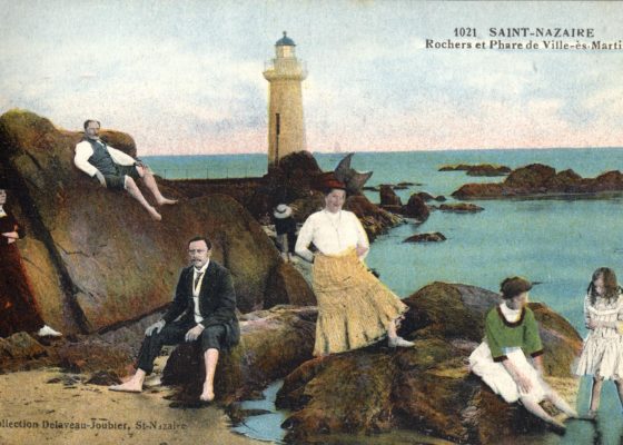 Carte postale représentant une famille posant de façon humoristique sur les rochers de la plage Villès-Martin vers 1910.