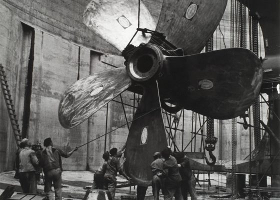 Photographie en noir et blanc représentant la pose d'une hélice de navire par des ouvriers vers 1955.