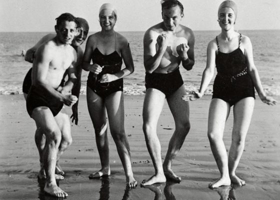 Photographie en noir et blanc d'un groupe posant sur une plage.